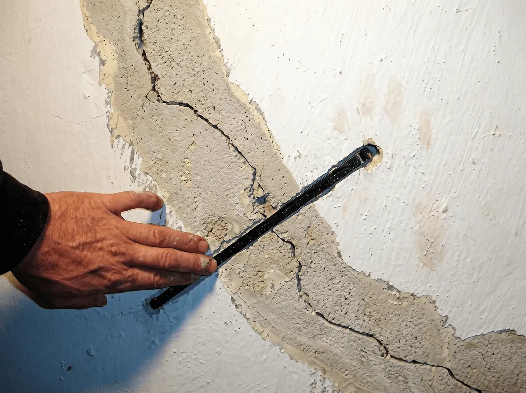 A wall with a large crack is being inspected by a professional in Huntsville, AL